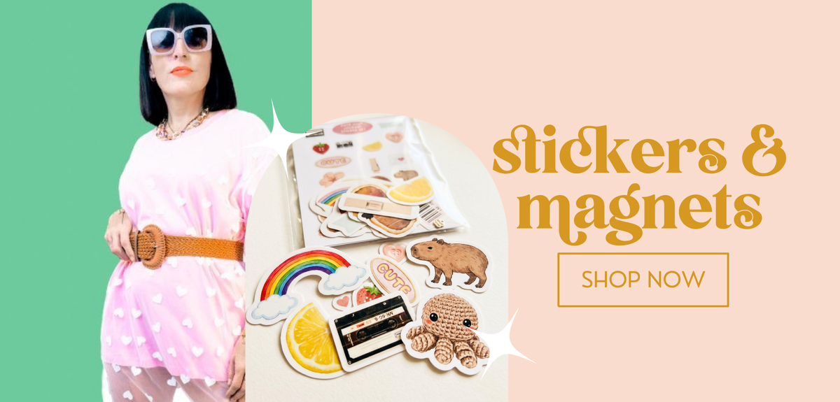 A promotional banner featuring a woman in a pink polka-dot dress and sunglasses holding a sheet of stickers, alongside several individual stickers and magnets shown on a cream surface. The right side has a peach background with the text 'stickers & magnets' and a 'SHOP NOW' button.