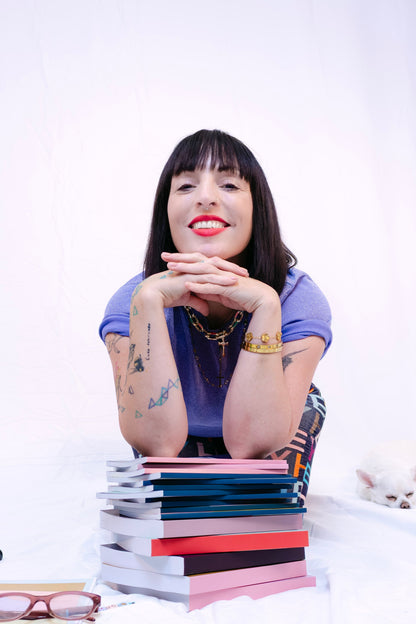 Woman sitting in a studio with books and stationery items